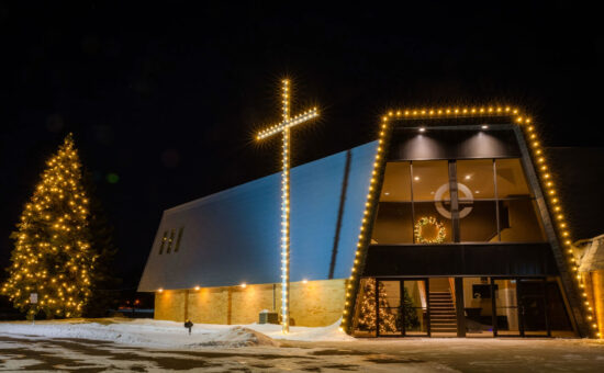 warm white christmas lights lining roof and tree of church