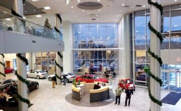 inside of car dealership business decorated with holiday lights and garland wrapped around pillars