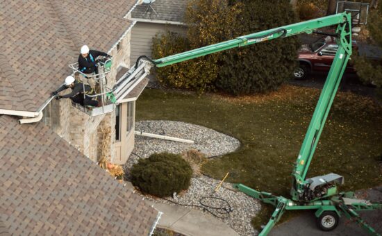 technician using a lift to hang Christmas lights on a roofline of residential home