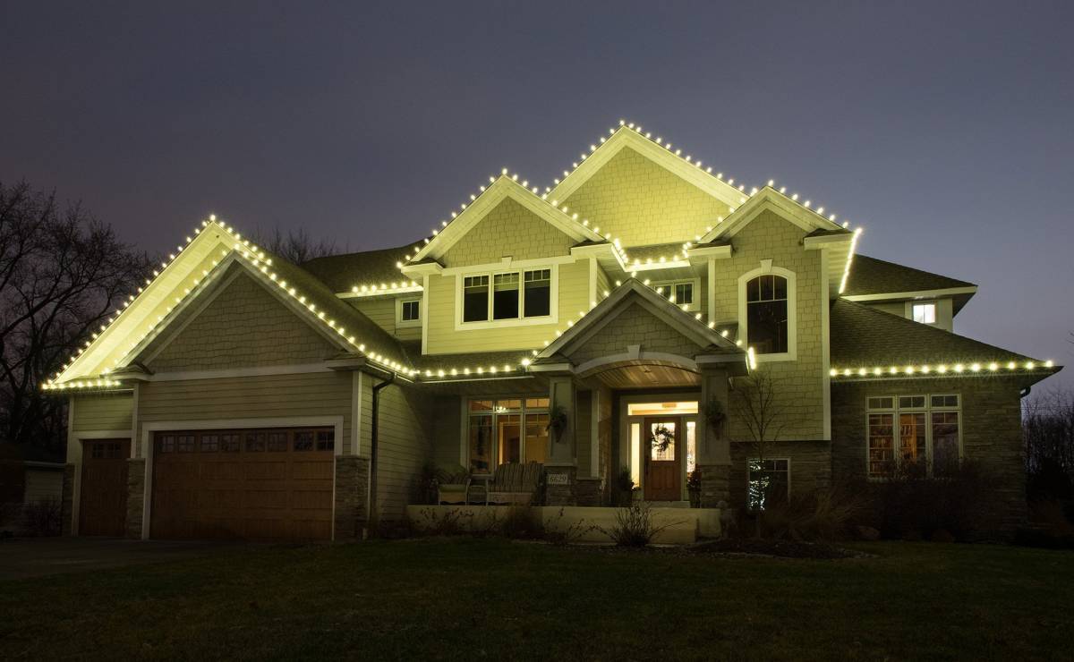 Two story house in Edina with multiple peaks in roof line decorated with white Christmas lights.