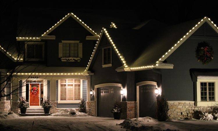 Warm white lights along peaks and roofline of Minneapolis home